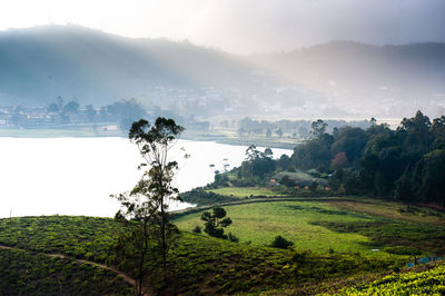 Scenic view of lake by mountains during foggy weather