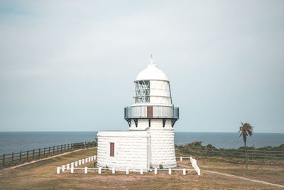 Lighthouse by sea against sky