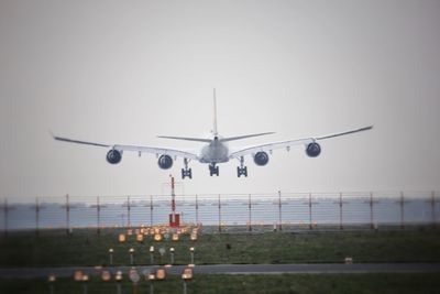Airplane flying over airport runway against clear sky
