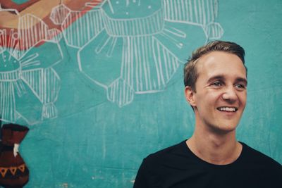Portrait of smiling young man against wall