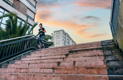 Female runner training down stairs over in urban runway on sunset