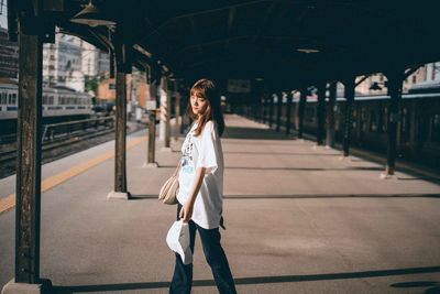 Full length portrait of woman standing at railroad station