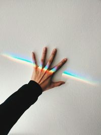 Colorful light beam falling of person hand on wall