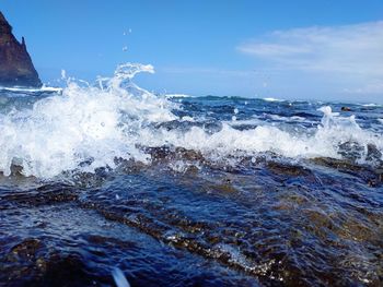 Waves splashing in sea against sky