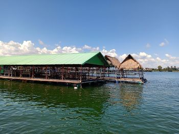 House by lake against sky