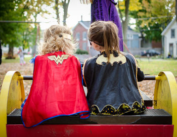 Rear view of superhero girls sitting on chair