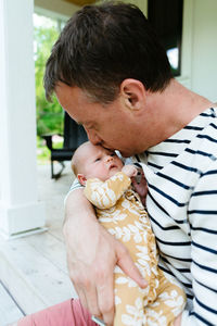 A new dad kissing his newborn baby girl on the forehead