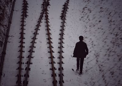 Rear view of man walking on snow covered land