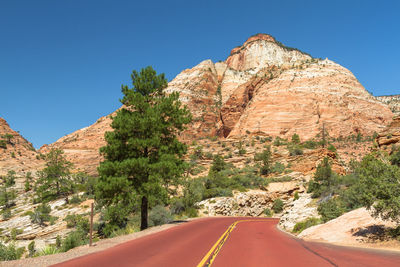 Road leading towards mountains against clear sky