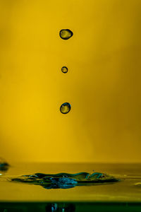 Close-up of water drops on glass against yellow background