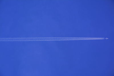 Airplane with vapor trail in blue sky