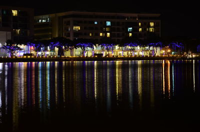 Illuminated building by river at night