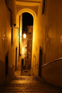 Illuminated street amidst buildings in city at night