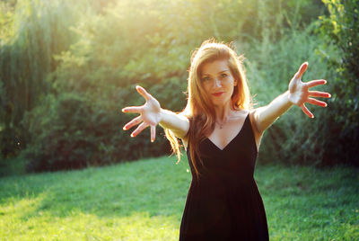 Portrait of young woman standing against tree