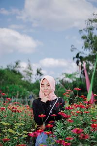 Portrait of young woman wearing hijab by flowering plants in park