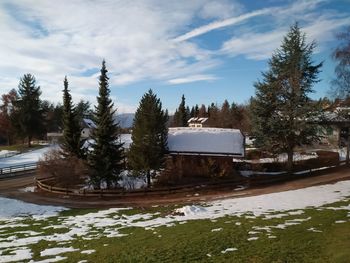 Built structure by trees against sky during winter