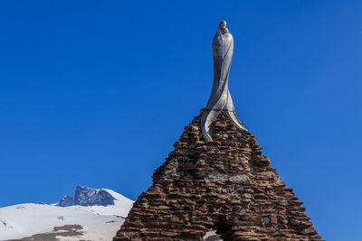 Low angle view of statue of building against blue sky