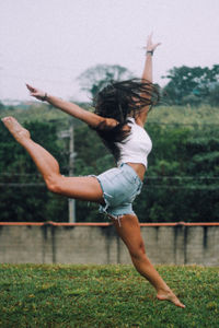 Full length of a young woman jumping on grass