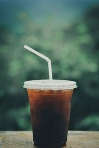 Ice coffee espresso, cappuccino, latte in plastic cup and white staw on wooden table