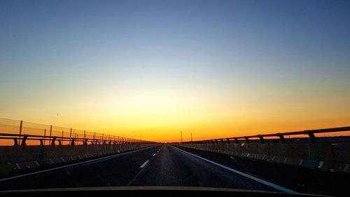 Bridge over road against sky during sunset