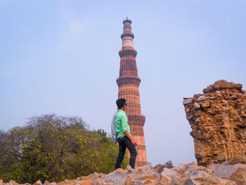 Rear view of man standing on rock against sky