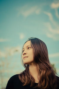 Thoughtful young woman looking away against sky