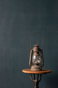 Close-up of old lantern on table against wall
