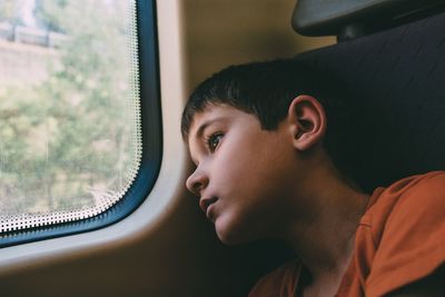 Close-up of thoughtful boy looking away while traveling in train