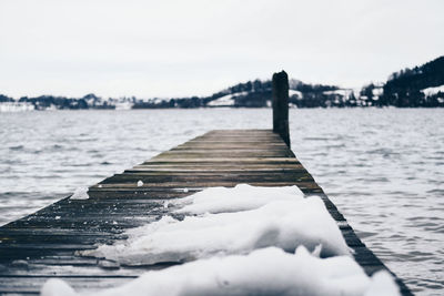 Pier on frozen lake against sky