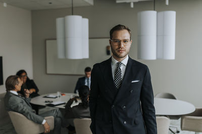 Portrait of confident young businessman standing in board room during meeting