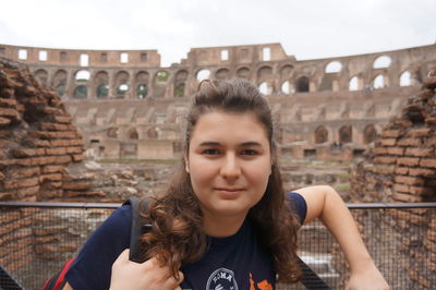 Portrait of young woman against historic building