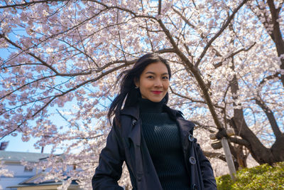 Portrait of a smiling young woman standing against trees