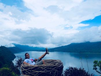 Man sitting in lake against sky