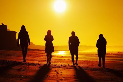 Silhouette people on beach at sunset