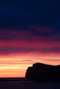 Scenic view of sea against dramatic sky during sunset