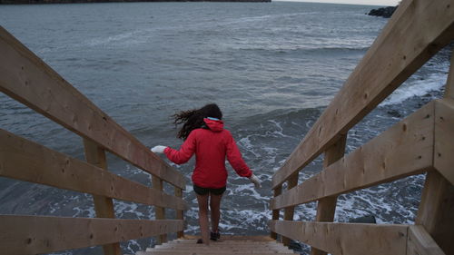 Rear view of woman walking on steps against sea