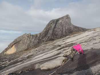 Female hiker climbing mountain against sky