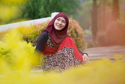 Smiling woman in headscarf sitting outdoors