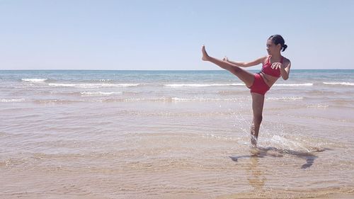 Woman enjoying at beach against clear sky