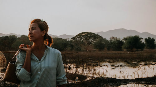 Portrait of young woman standing against sky during sunset