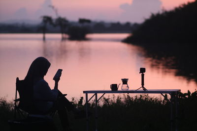 Rear view of silhouette man photographing at sunset