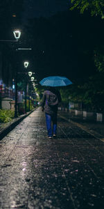 Rear view of man walking on street at night