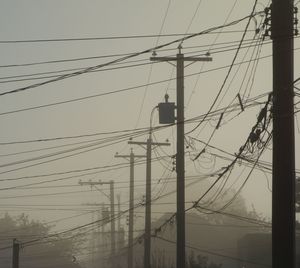 Low angle view of electricity pylon against sky during sunset