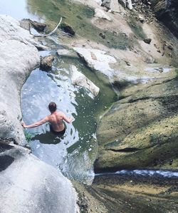 High angle view of shirtless man in pond at rocky mountains