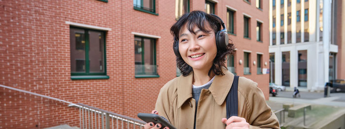 Young woman standing against building