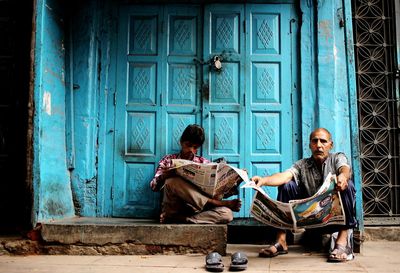 Couple sitting on closed door of building