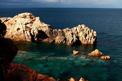 Rock formations by sea against sky