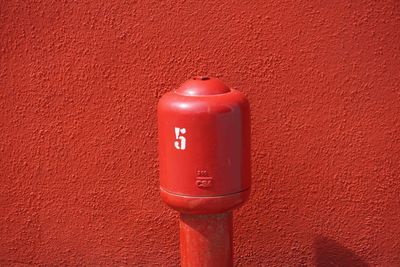 Red metallic bollard against wall