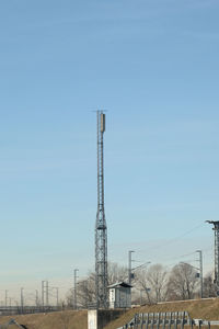 Electricity pylon by factory against clear sky