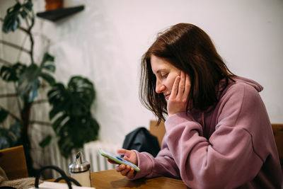 Young woman using mobile phone at cafe